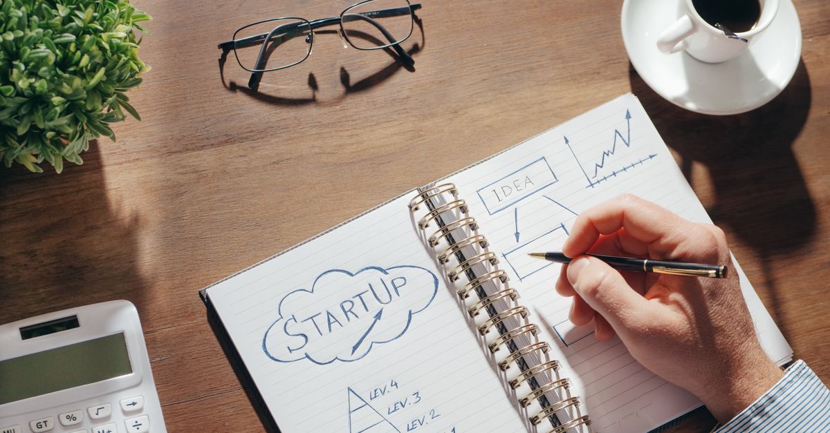Close up of a person writing notes in a notebook while planning a business