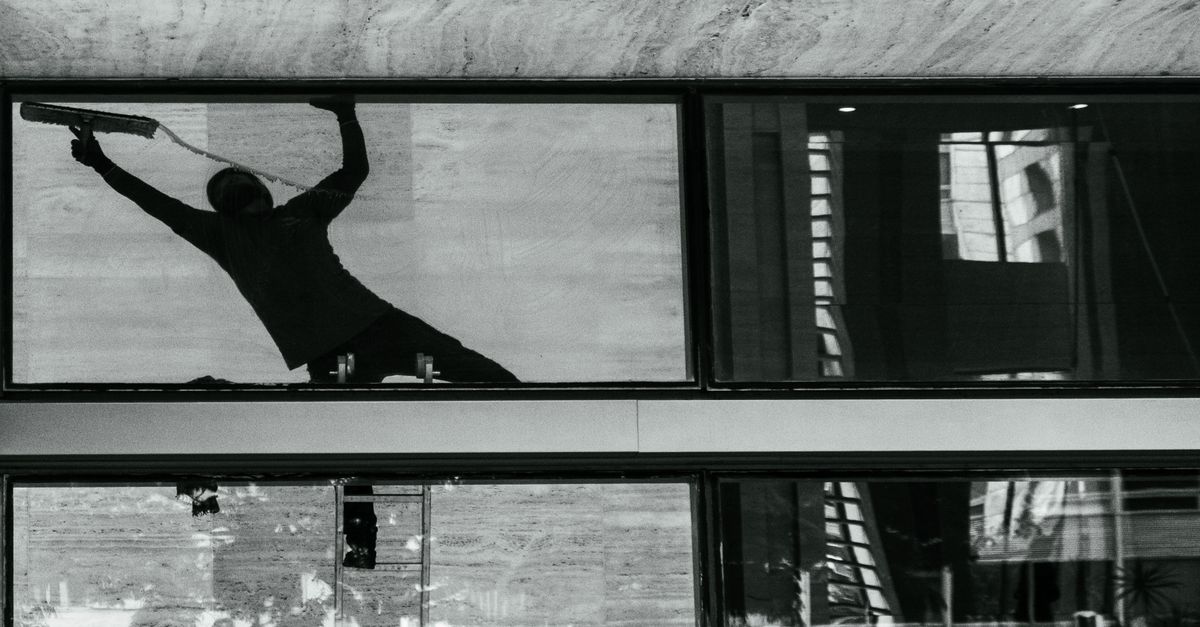 Silhouette of a window cleaner working on a large pane of building glass